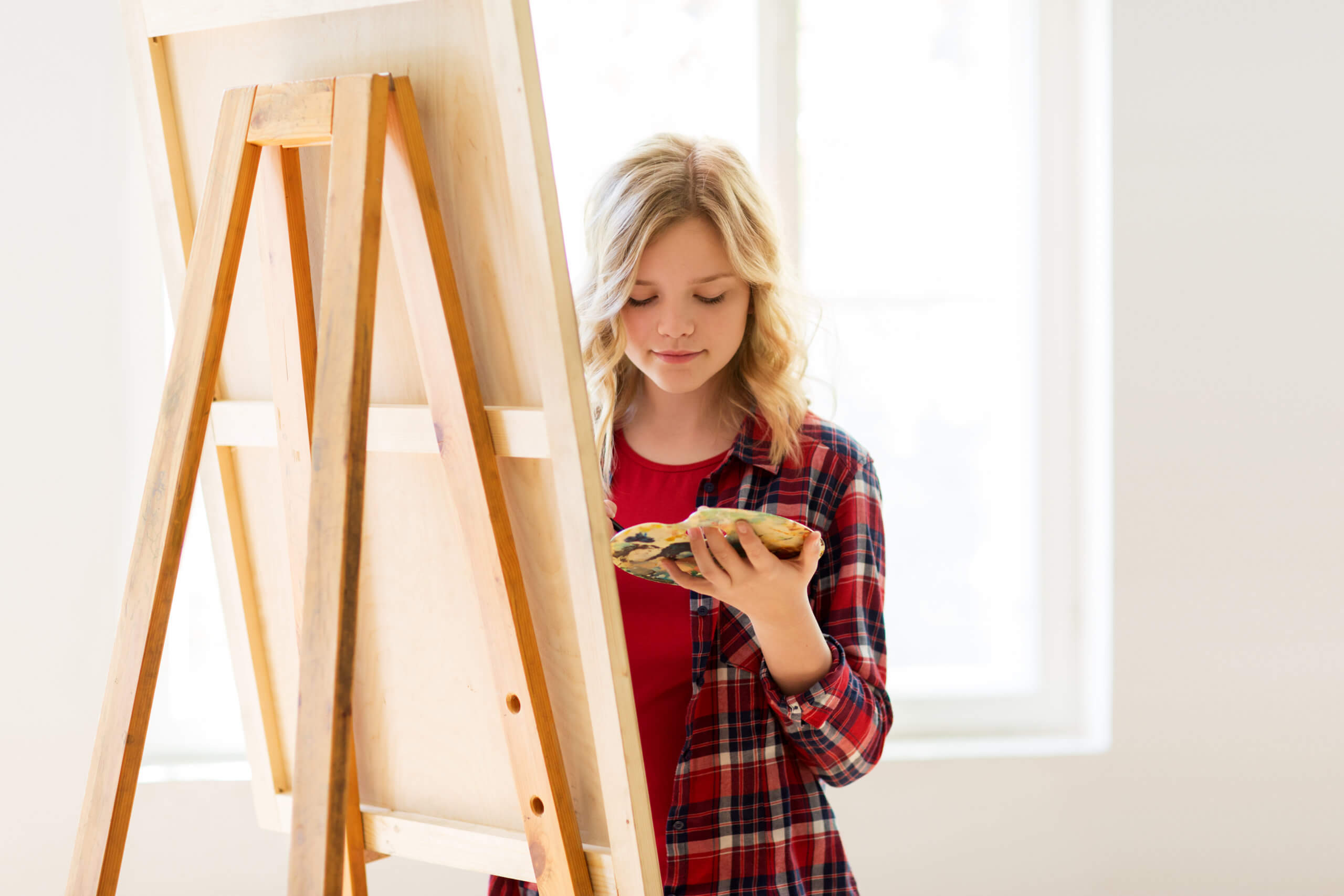 student girl with easel painting at art school PVPQ9UA scaled